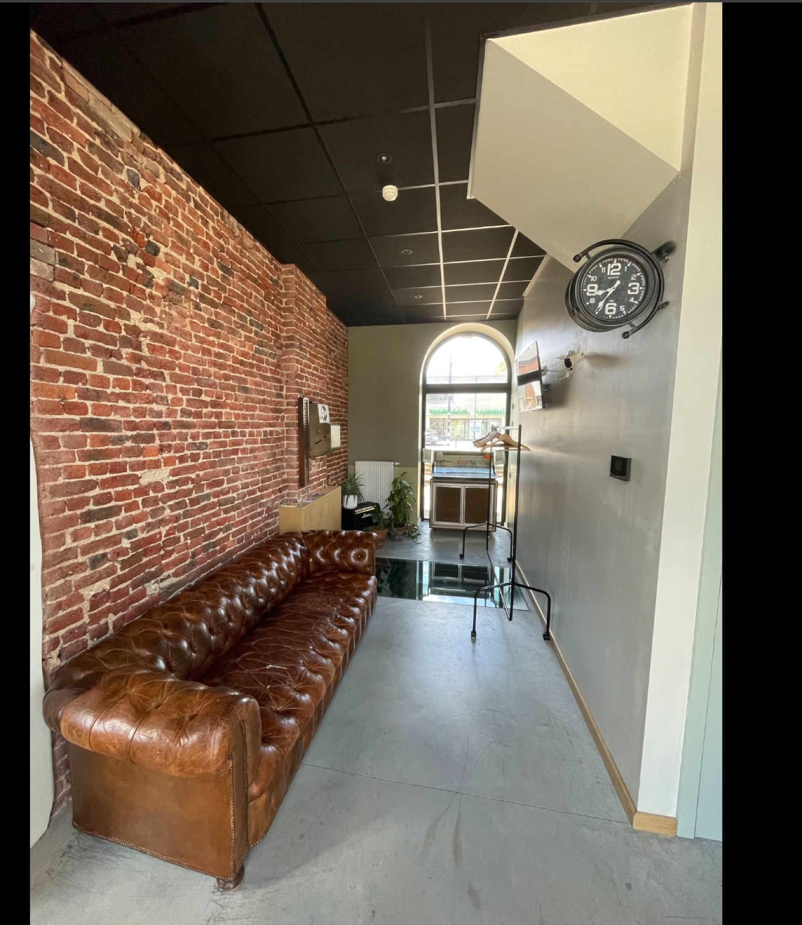 Coin accueil de l'école Music Factory à Haversin, canapé en cuir et briques apparentes